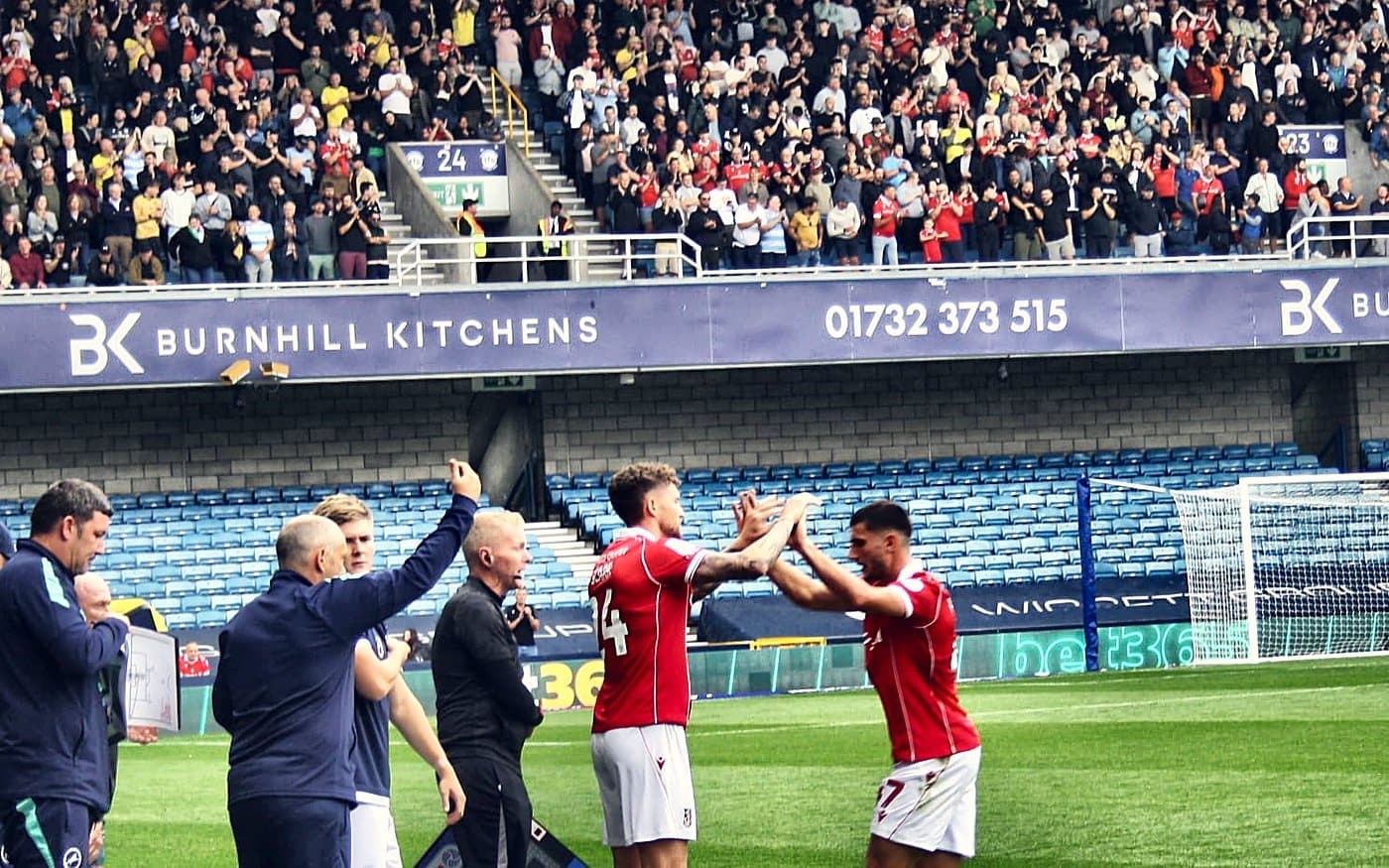 Wrexham players high-five on the touchline at Millwall, August 2025