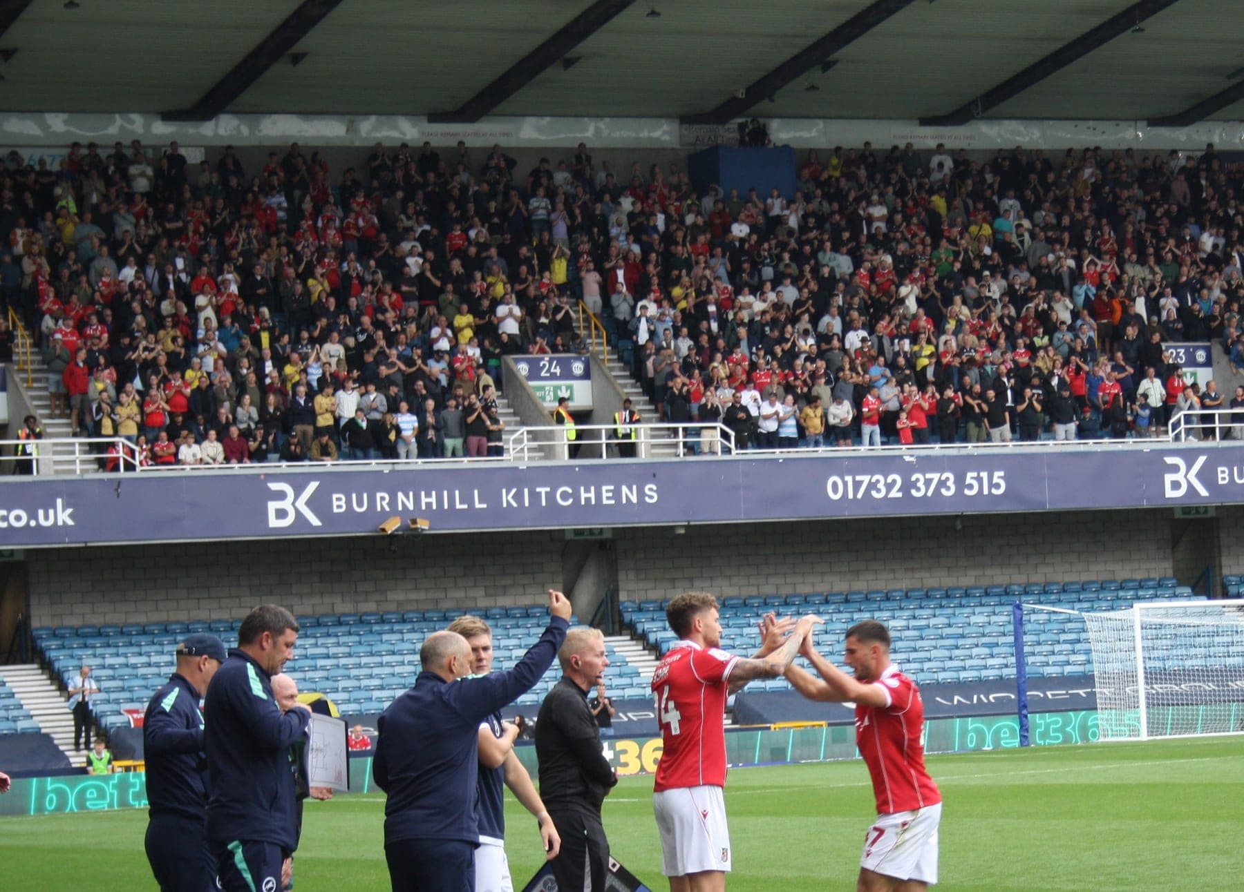 Wrexham players high-five on the touchline at Millwall, August 2025